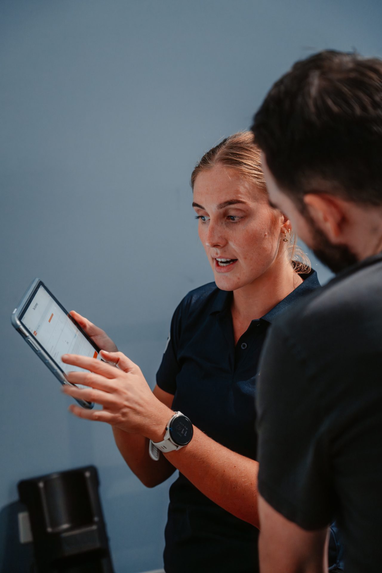Exercise physiologist reviewing performance testing results on a tablet with a client at PerforMotion