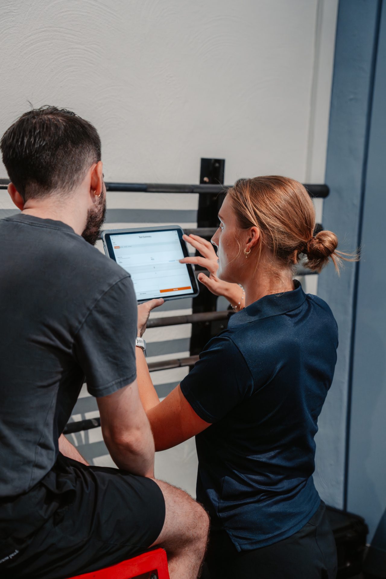 Exercise physiologist working through a program on a tablet with a client at PerforMotion